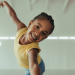 A child with diverse abilities joyfully dancing in an adaptive dance class, illustrating growth and self-expression.